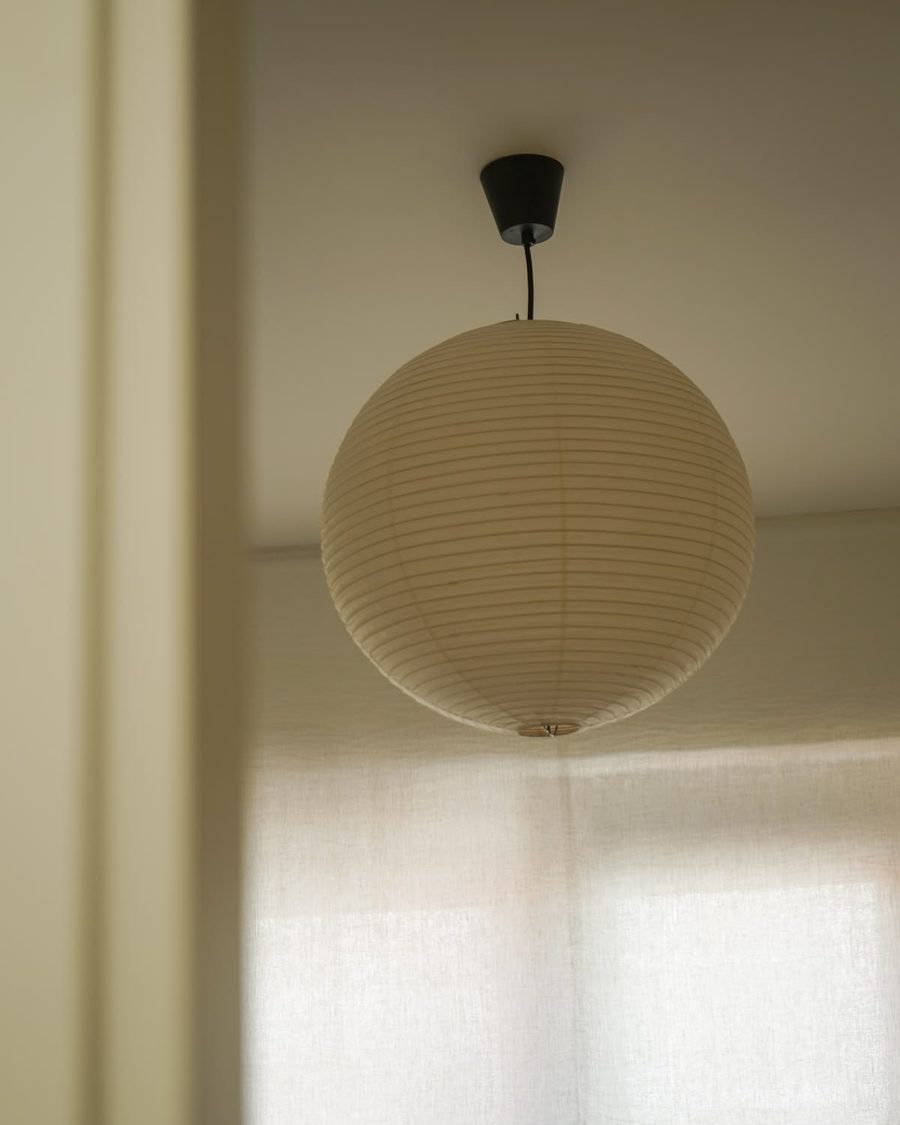 Isamu Noguchi AKARI 30A pendant hanging by a window: a round washi paper shade on bamboo ribbing