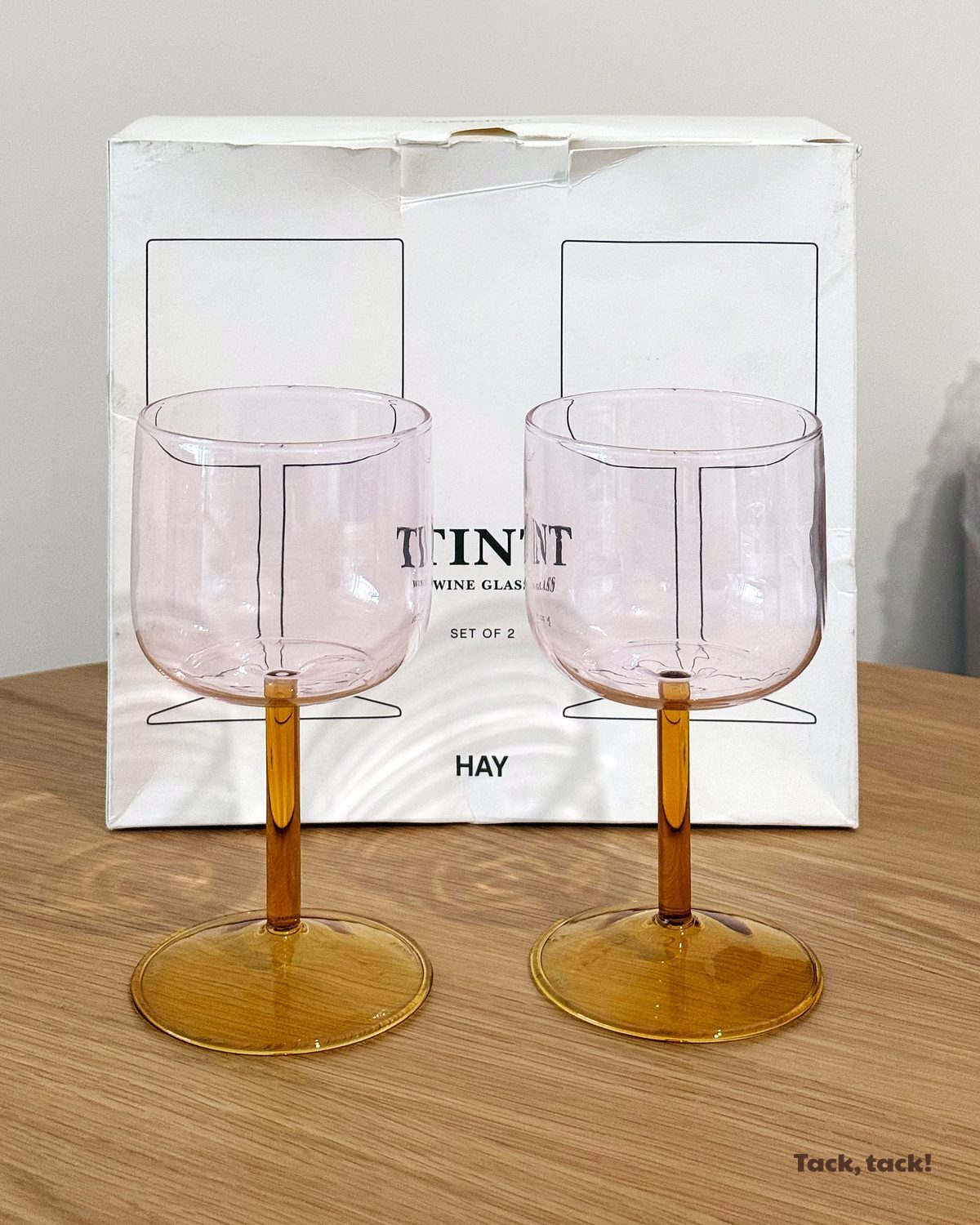 HAY Tint 酒杯兩隻裝,粉紅色杯身配黃色杯柄及杯腳,放在白色桌面上